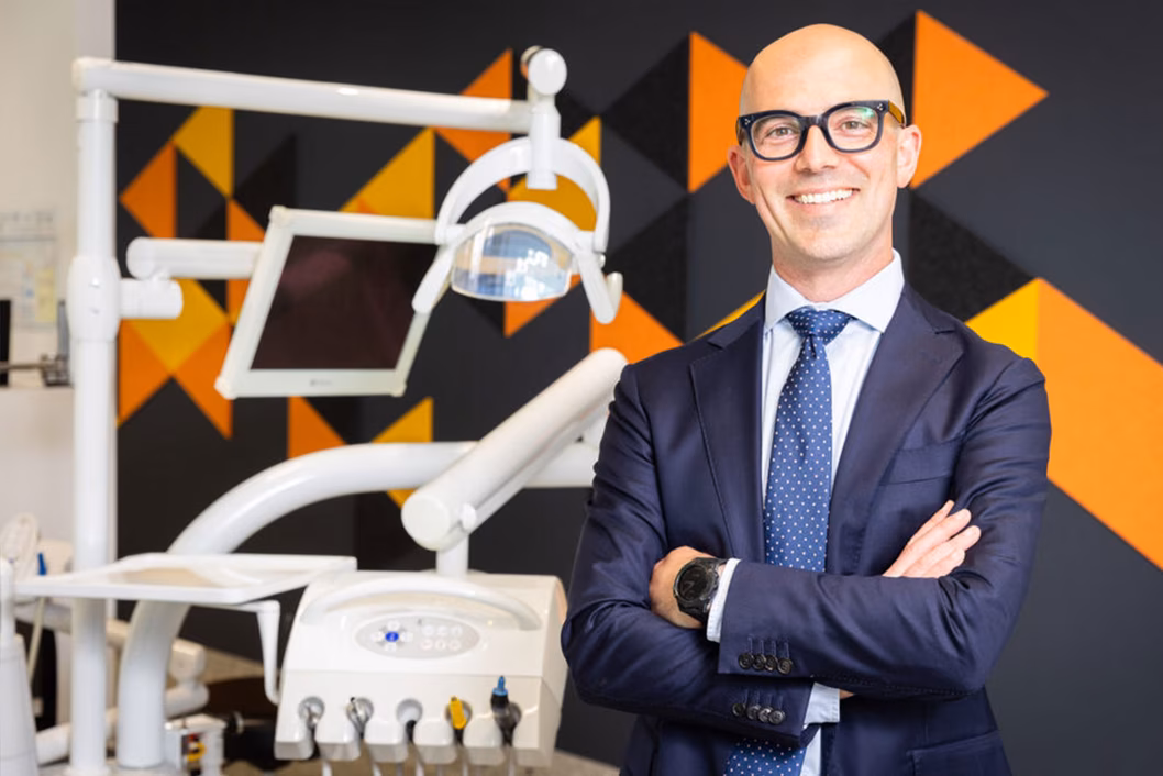 Photo of a man smiling next to dentist equipment