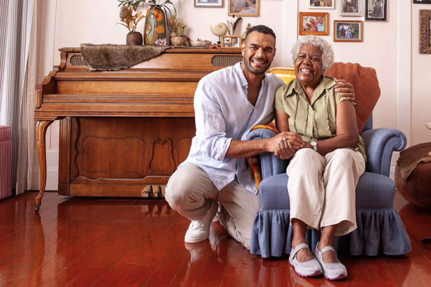Photo of a young man embracing an older lady in a blue armchair