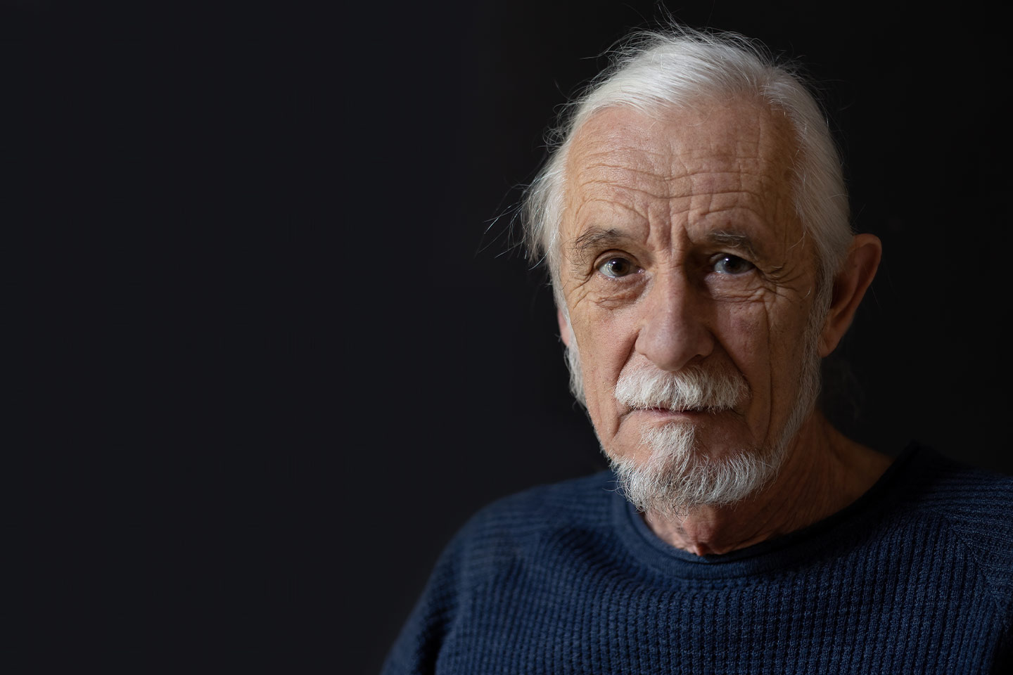 Photo of a man with white goatee on a dark background