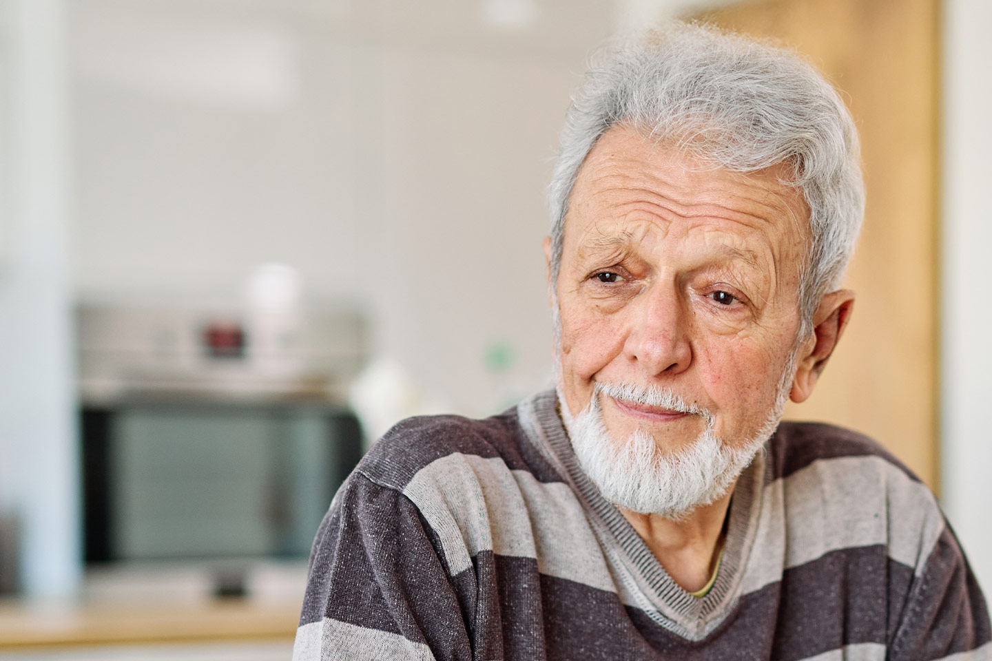 Photo of a bearded man wearing a brown and grey striped t-shirt