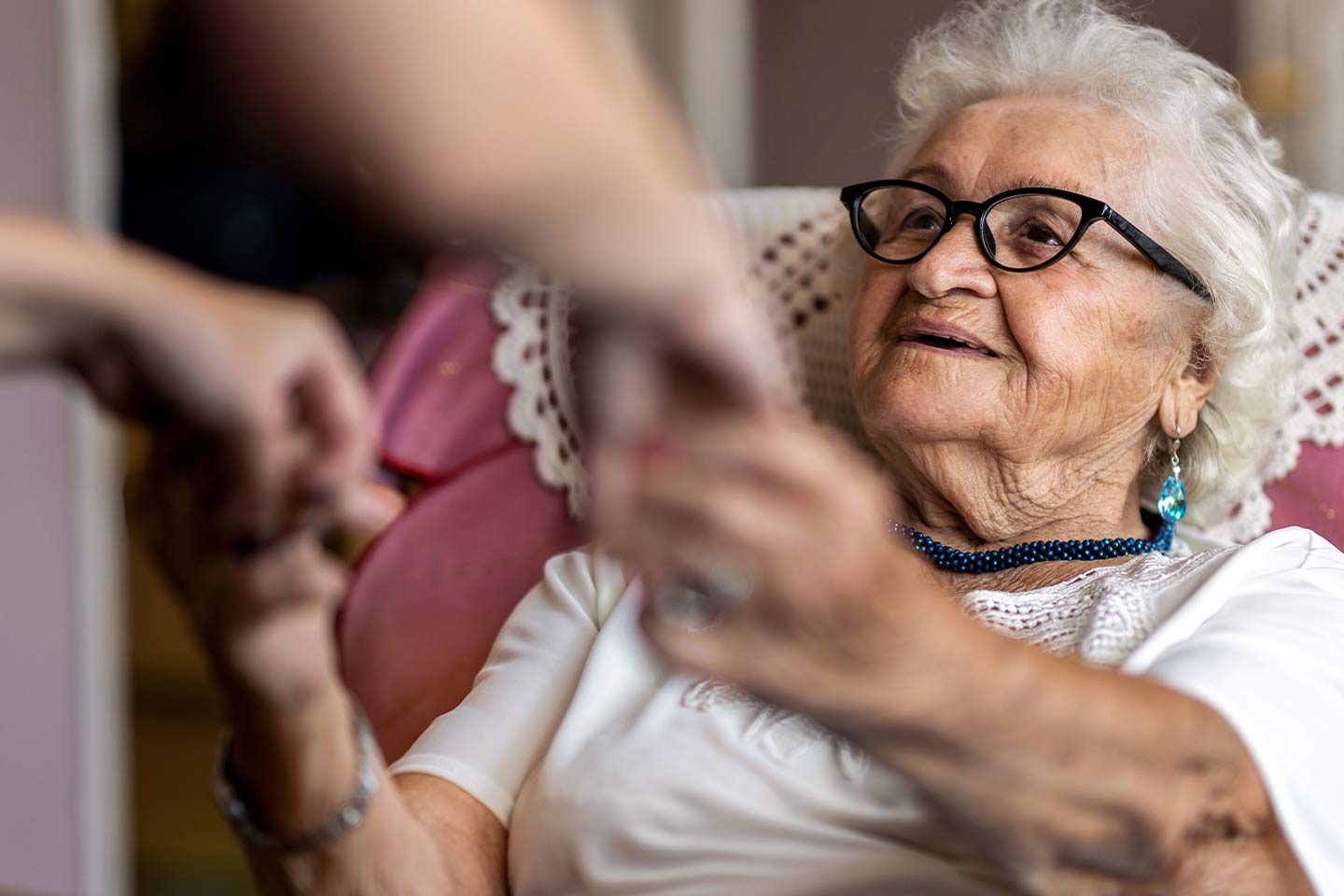 Photo of woman in a pink chair holding hands with another person