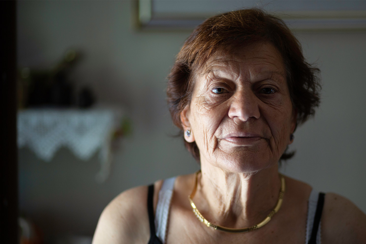 Photo of a woman in a dim room wearing a gold necklace