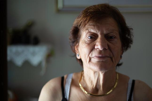 Photo of a woman in a dim room wearing a gold necklace
