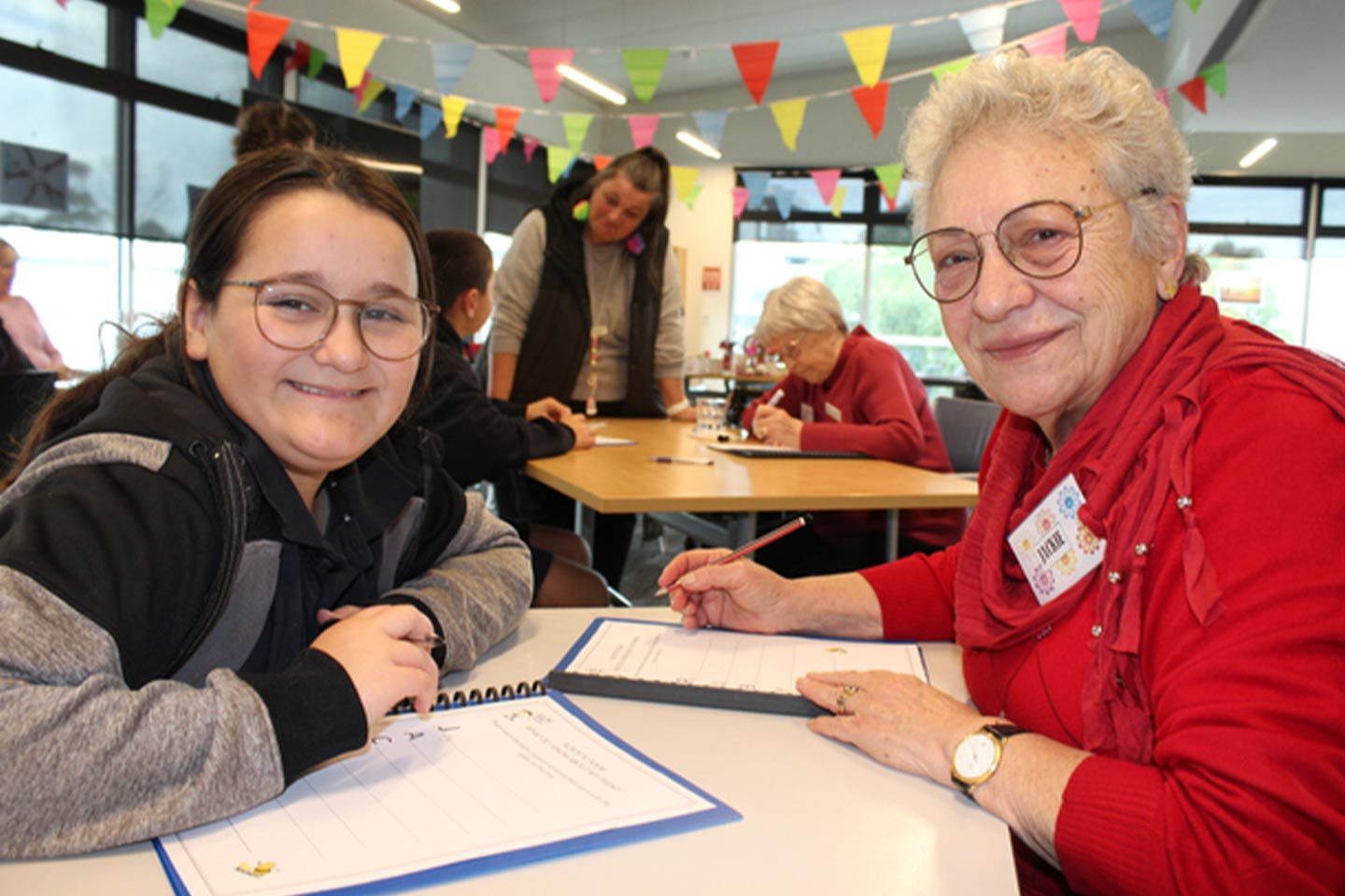 Photo of smiling girl and older woman sitting at a table