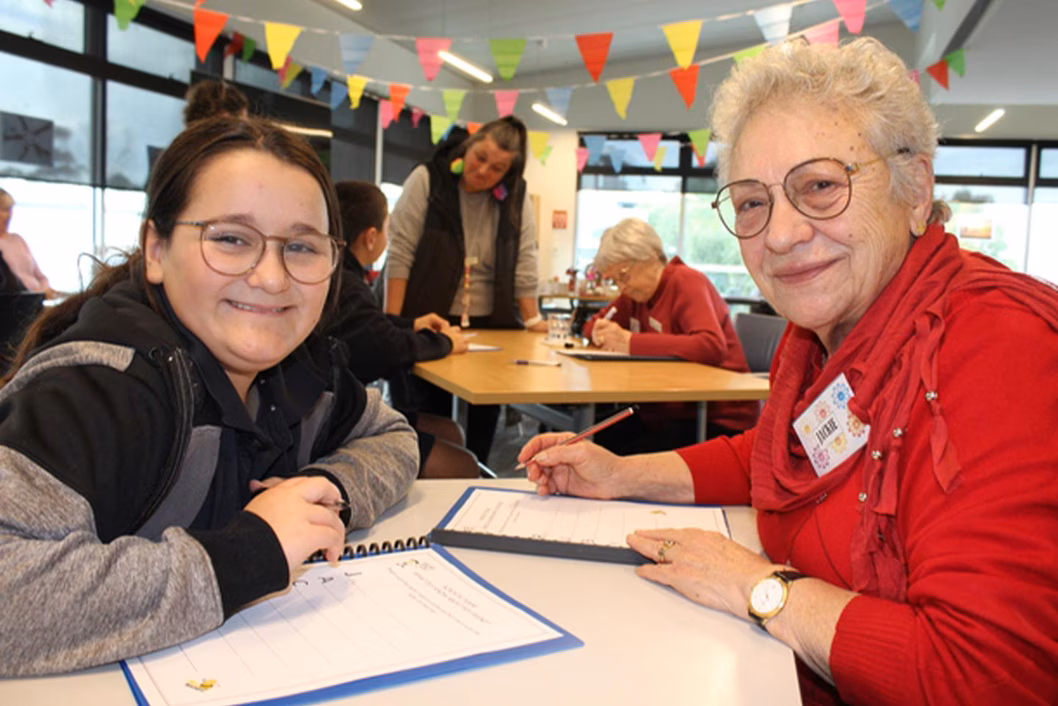 Photo of smiling girl and older woman sitting at a table