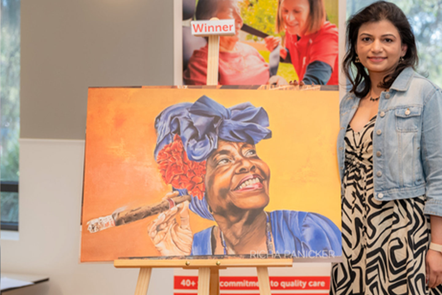 Photograph of woman standing next to a winning painting