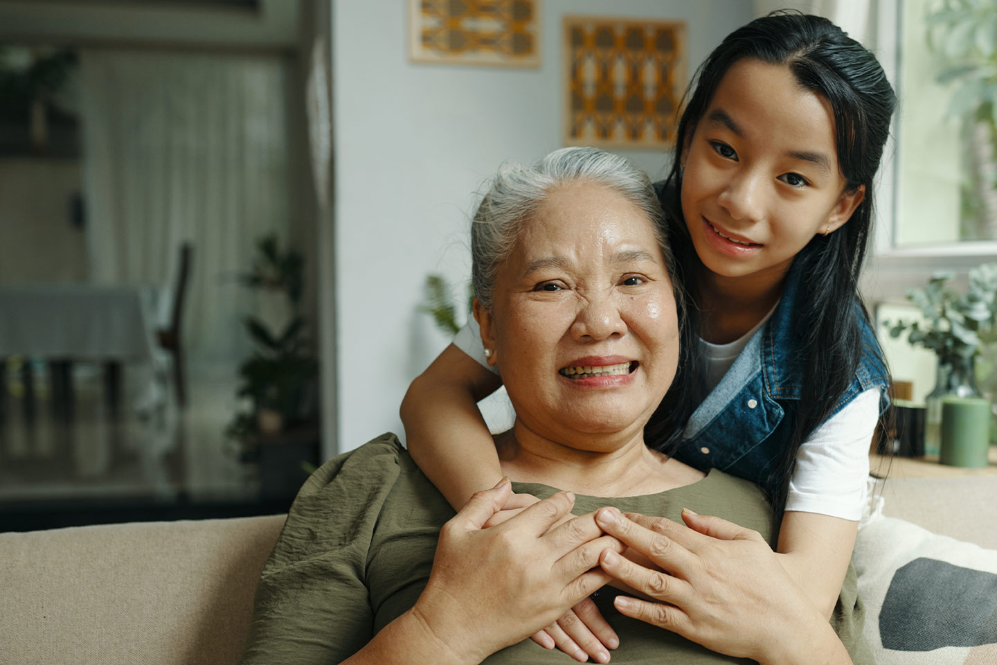 Photo of a young girl hugging an older woman from behind
