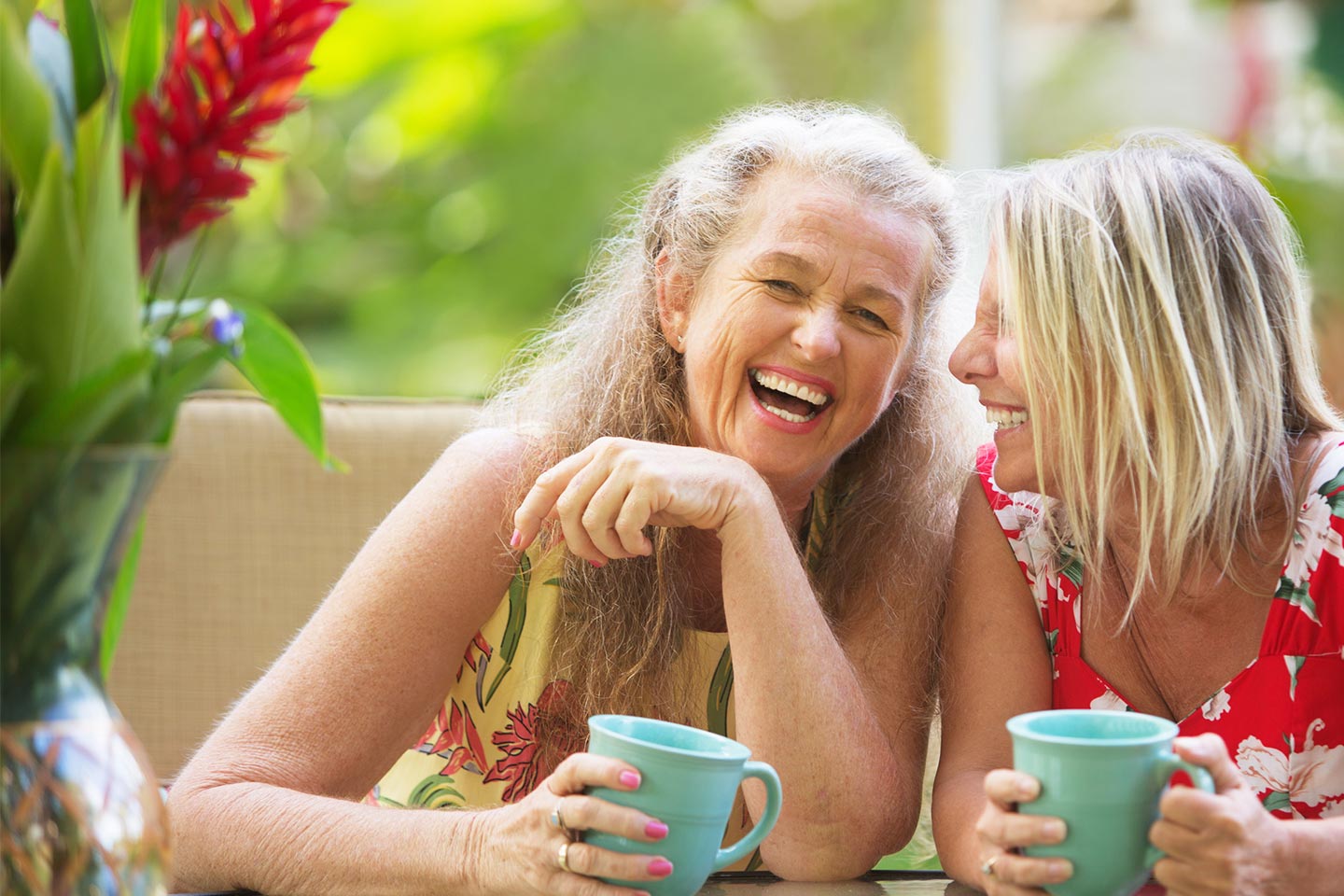 Photo of two women laughing in a tropical setting