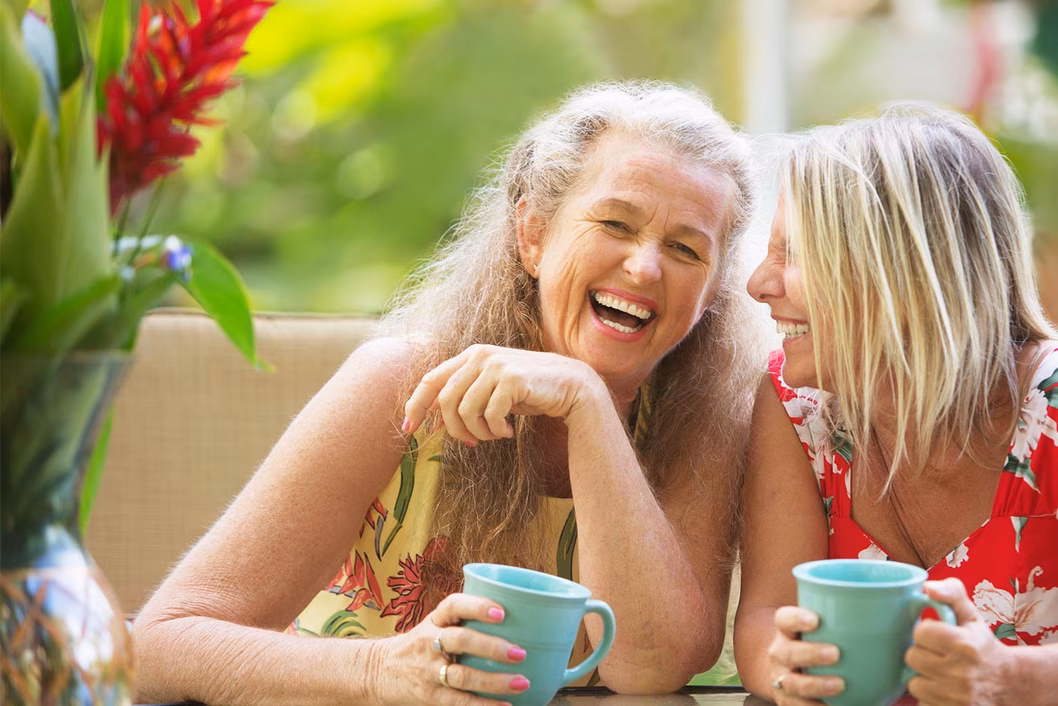 Photo of two women laughing in a tropical setting