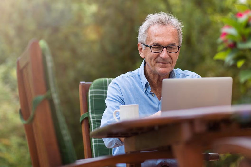 Photo of a man sitting in a garden with a computer