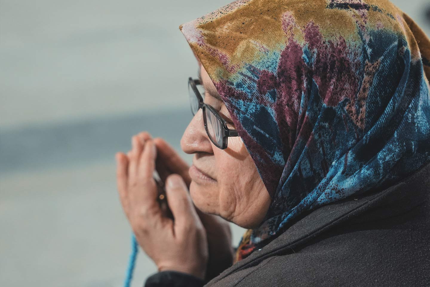 Photo of a praying woman with headscarf and rosary
