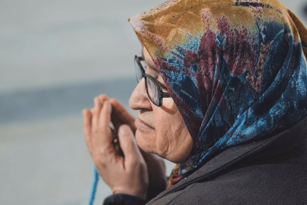 Photo of a praying woman with headscarf and rosary