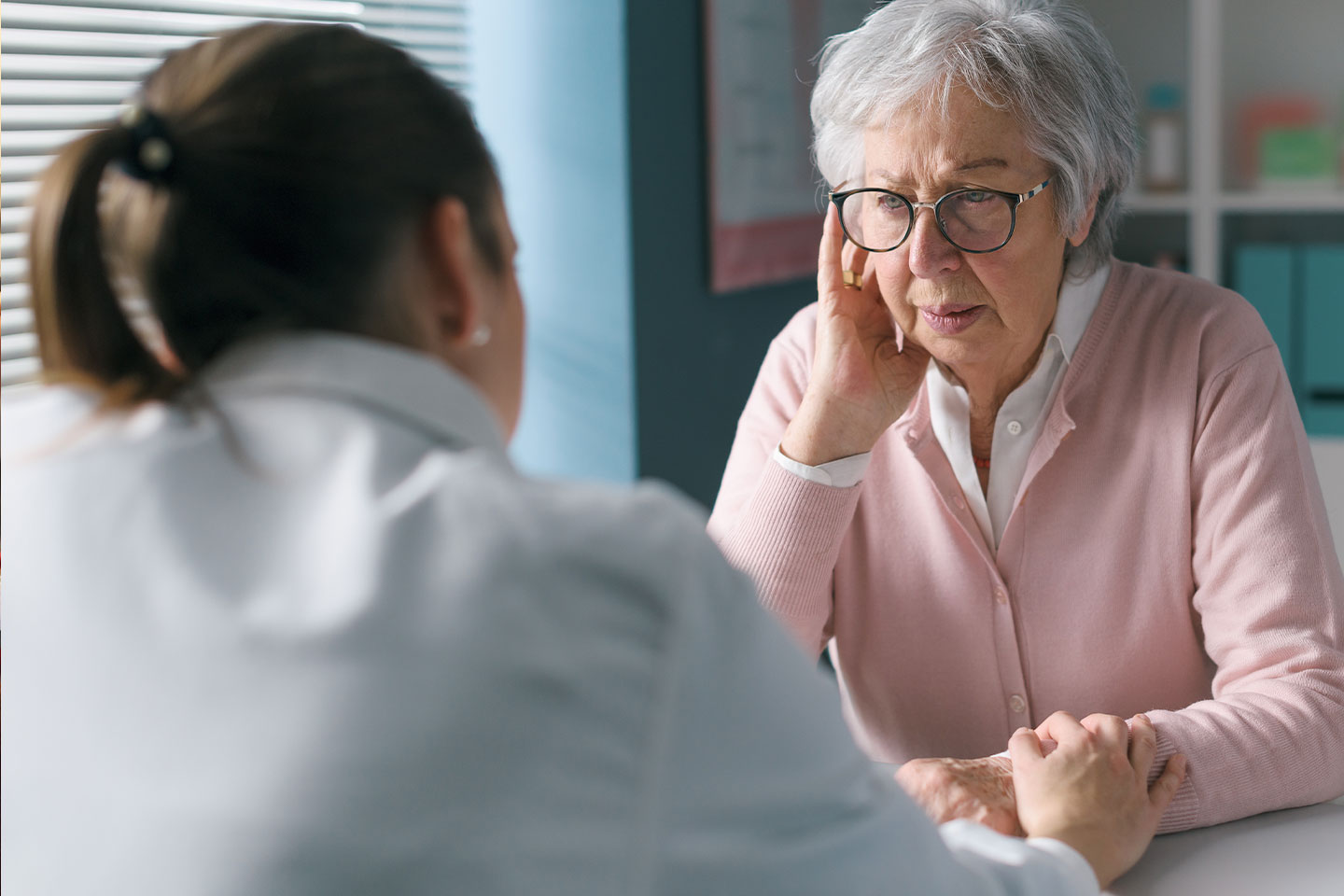 Photo of woman in a pink cardigan being comforted by a doctor