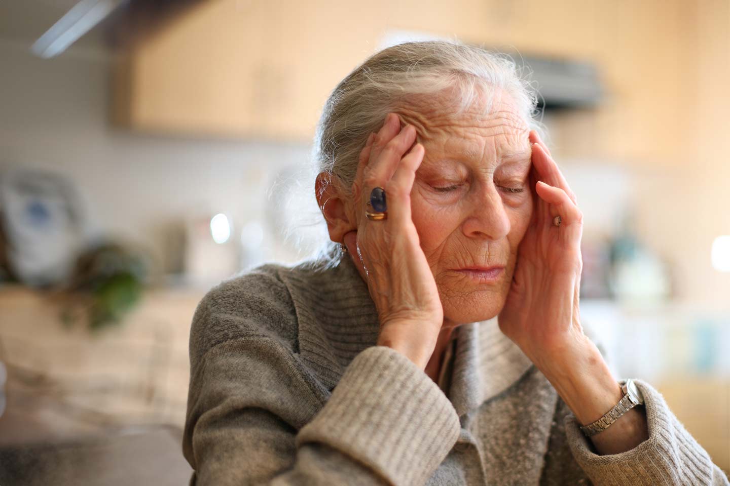 Photo of a woman in rubbing her temples with her eyes closed