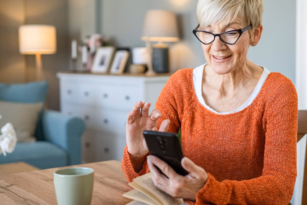 Photo of a woman in an orange jumper using her mobile phone