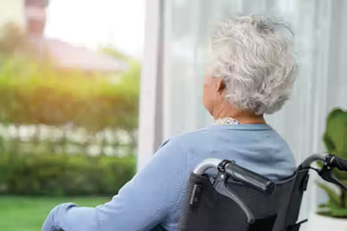 Photo of woman in a wheelchair looking out of a window
