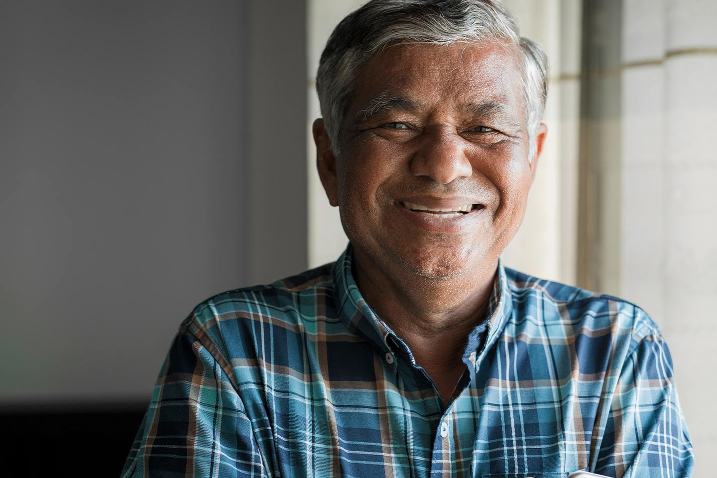 Photo of a laughing man in a blue plaid shirt