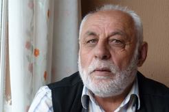 Image of an older bearded man who is sitting inside near a window