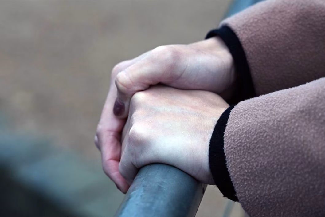 Photo of hands holding a metal hand rail