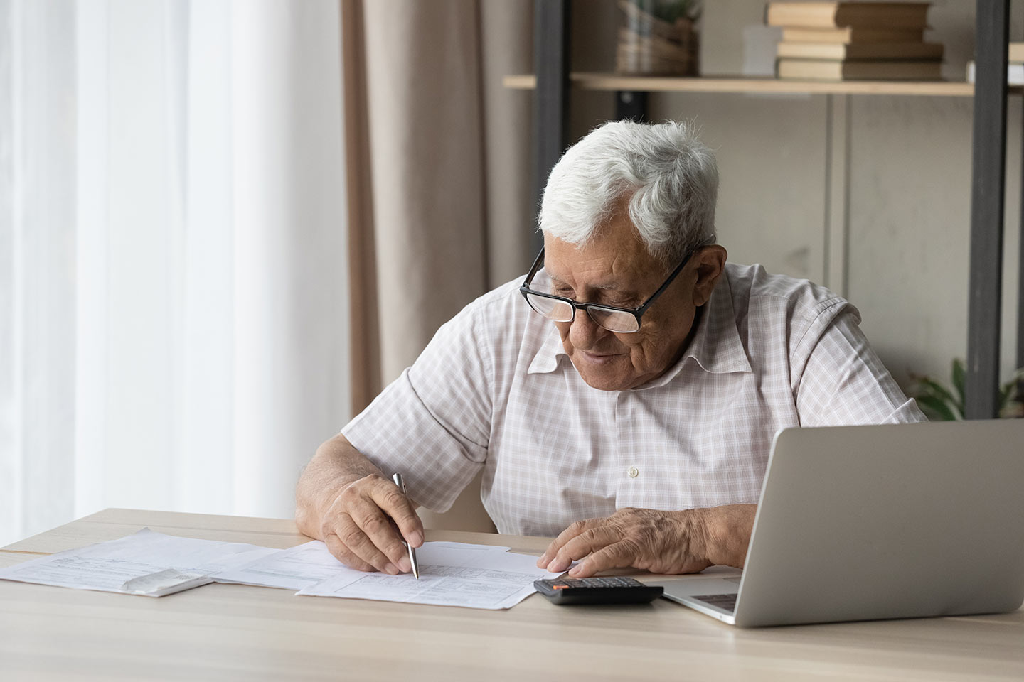 Image of an older man sitting at a desk reviewing paperwork