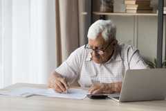 Image of an older man sitting at a desk reviewing paperwork