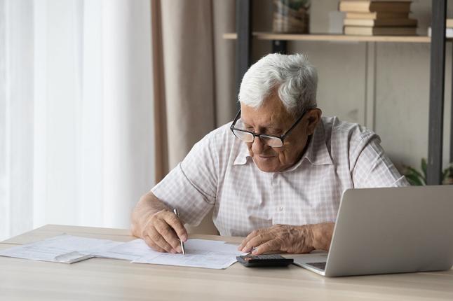 Image of an older man sitting at a desk reviewing paperwork