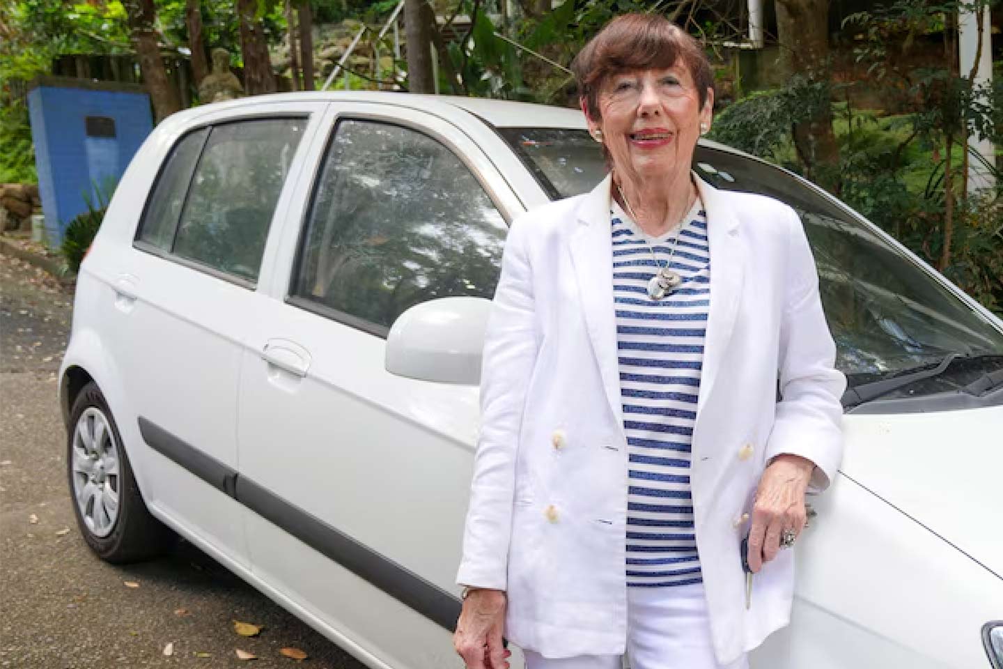 Photo of woman in white leaning on white car