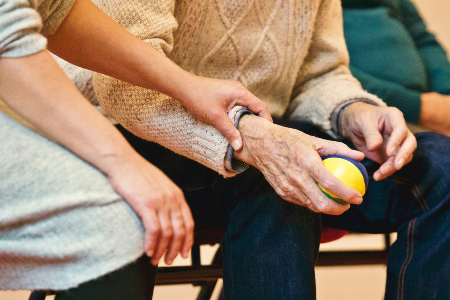 Photo of a hand clasping the wrist of a person holding a rubber ball