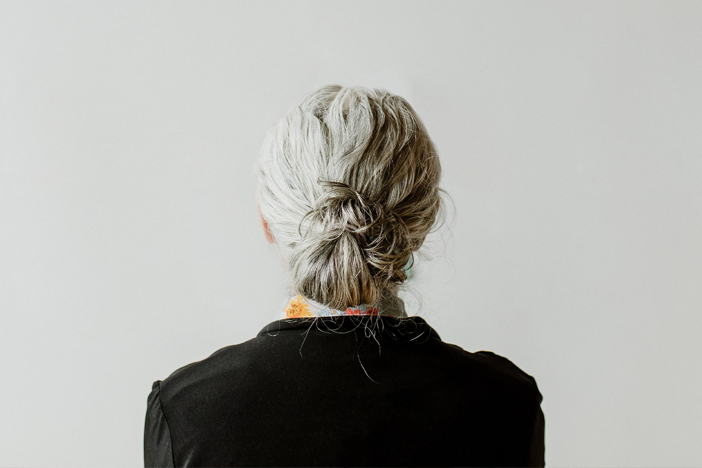 Photo of the back of a woman's head with her hair tied in a grey bun