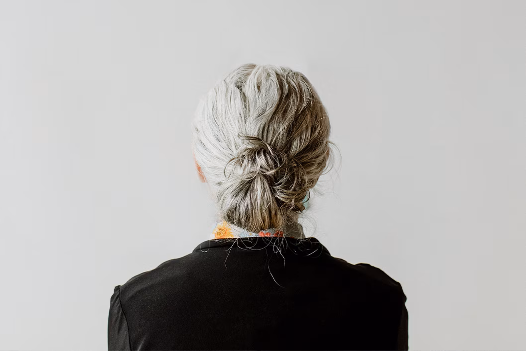 Photo of the back of a woman's head with her hair tied in a grey bun