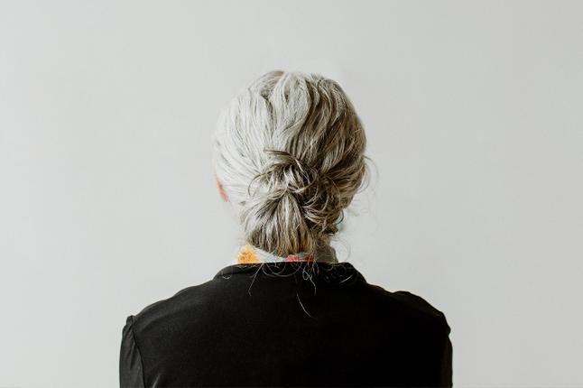 Photo of the back of a woman's head with her hair tied in a grey bun