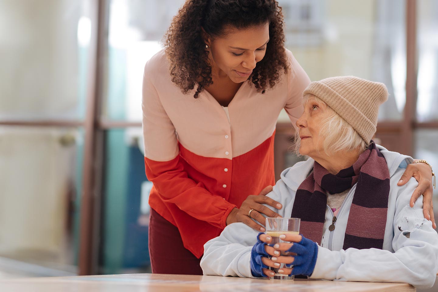 Photo of a woman comforting another in beanie and scarf