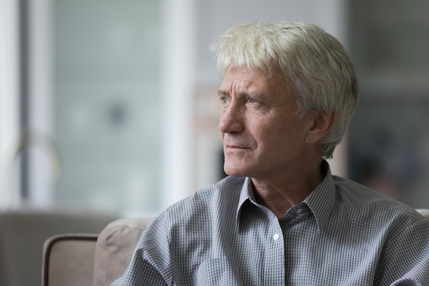 Photo of a man with white hair and a grey check shirt