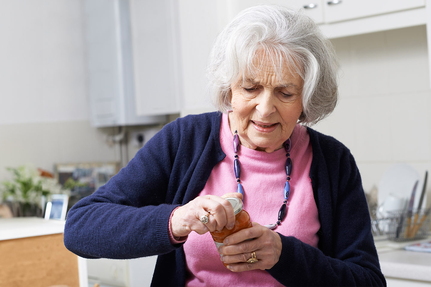 Photo of woman struggling to screw lid off jar