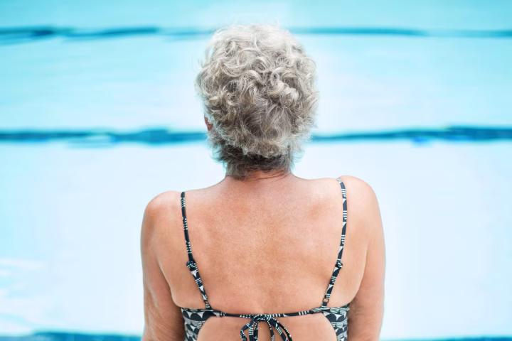 Senior woman sitting on edge of pool