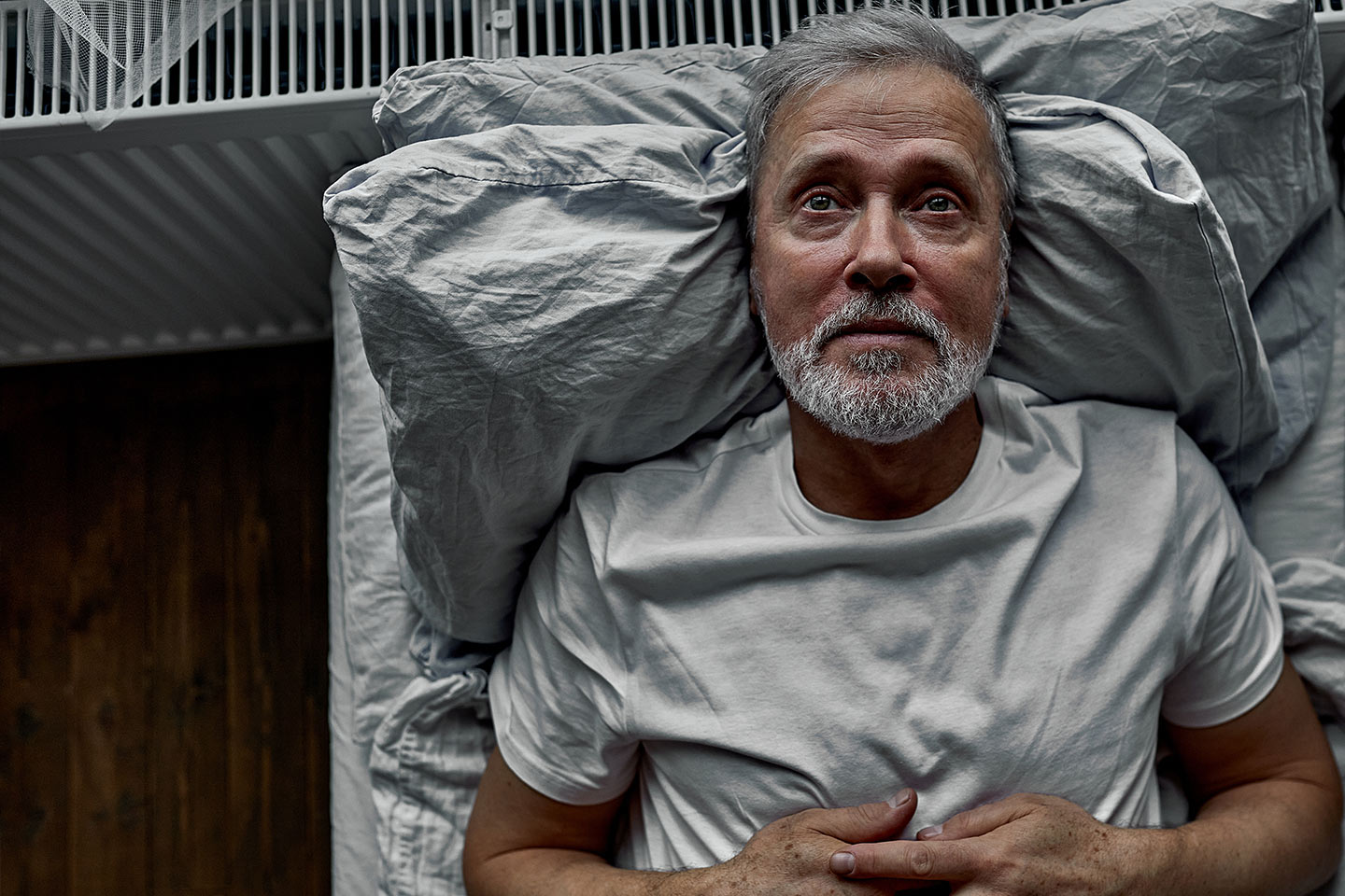 Photo of a man in a white T shirt lying on a bed