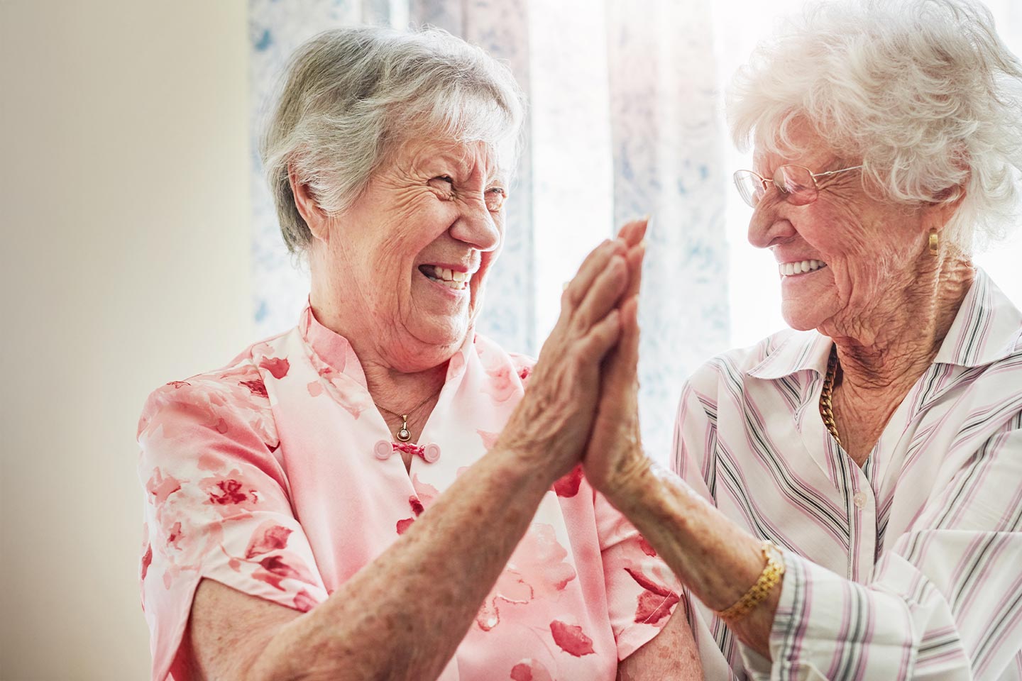 Photo of two woman laughing with palms touching