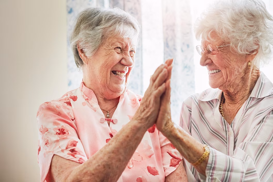 Photo of two woman laughing with palms touching