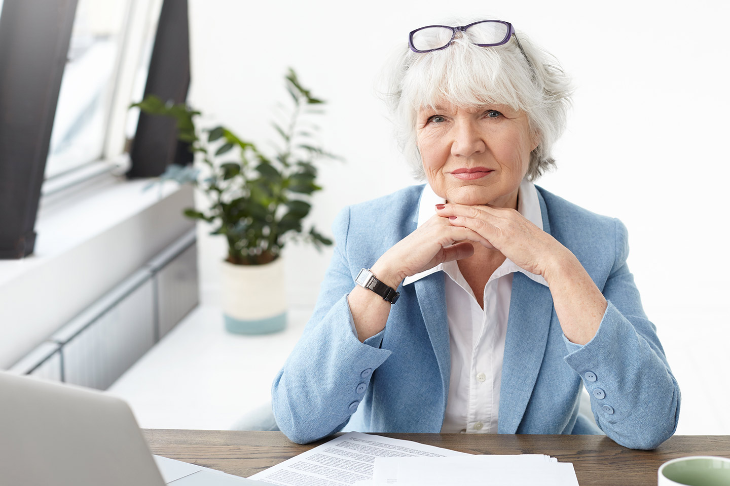 Photo of a business woman with white hair and a smart blue suit