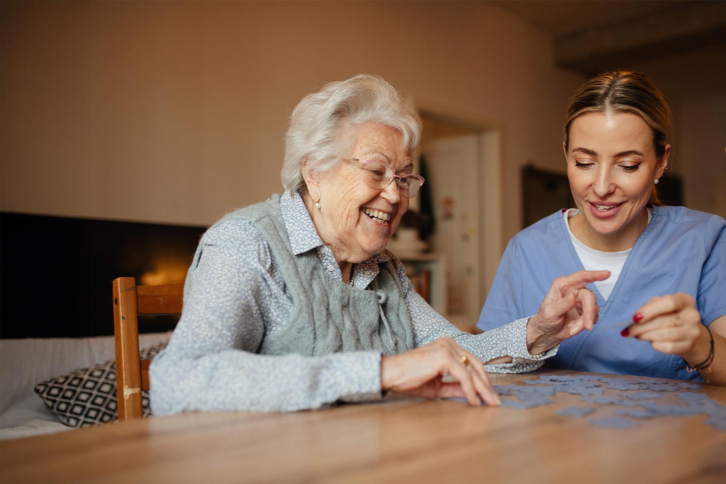 A woman and a health care worker do a jigsaw puzzle together