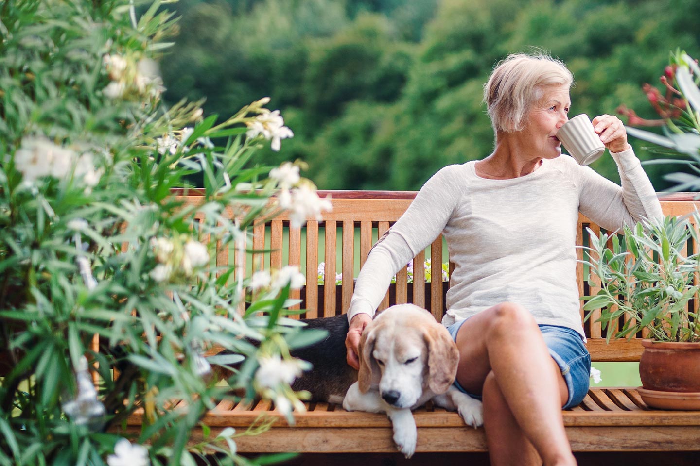 Photo of a woman outdoors with beagle and coffee