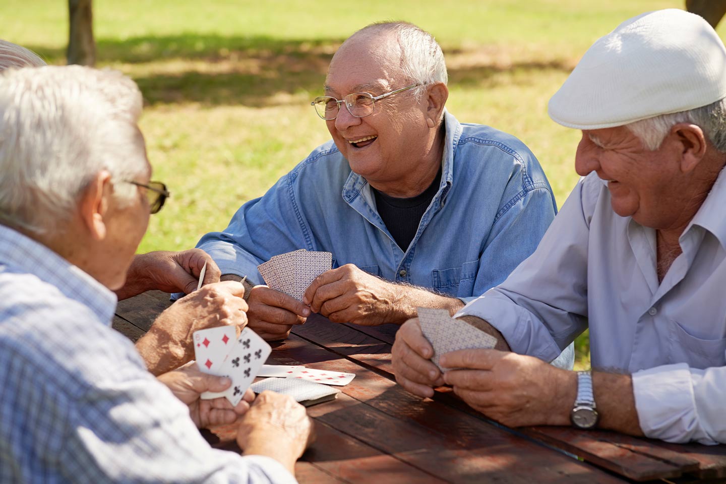 Photo of men playing cards at a picnic bench