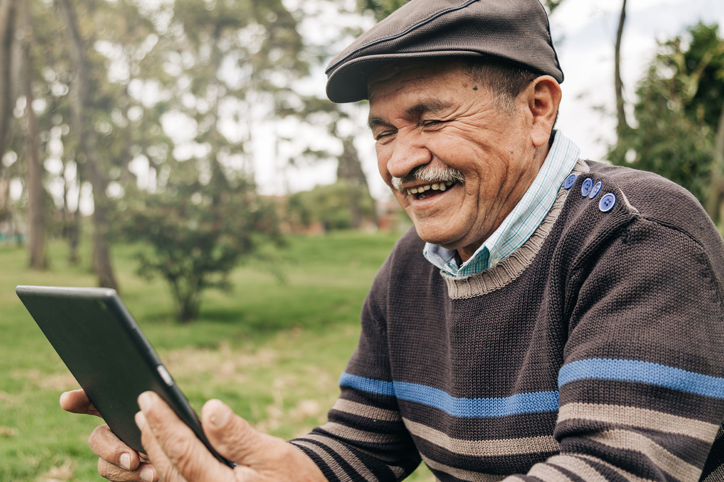 Image of an older man looking at an iPad and smiling