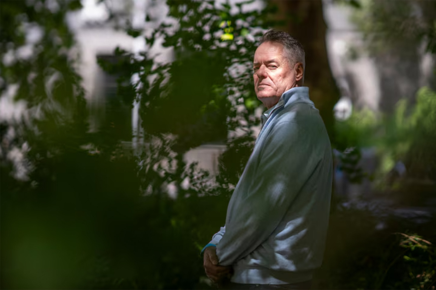 Photo of a man standing in a light dappled garden
