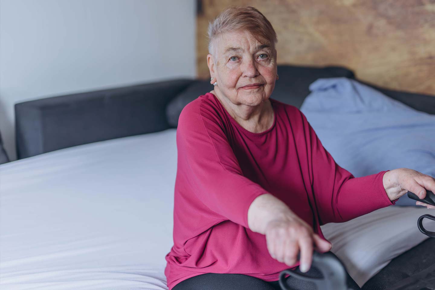 Photo of a woman wearing a magenta top sitting on a bed