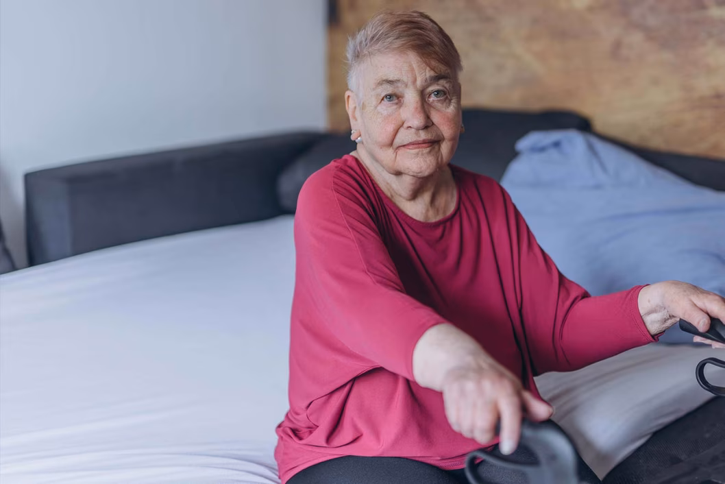 Photo of a woman wearing a magenta top sitting on a bed