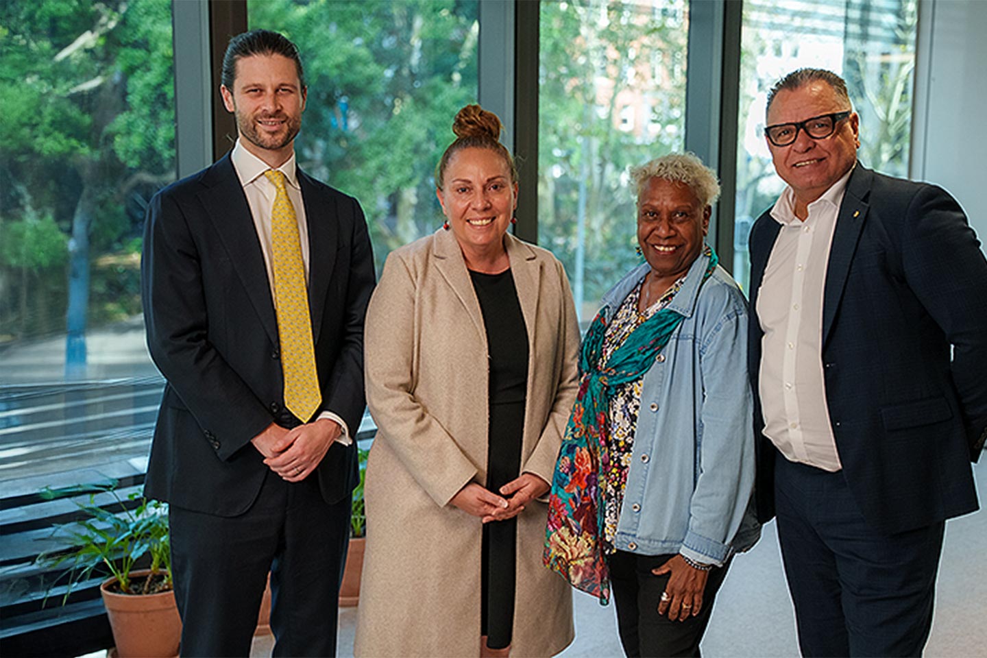 Photo of a group of four people wearing business casual clothes smiling at the camera