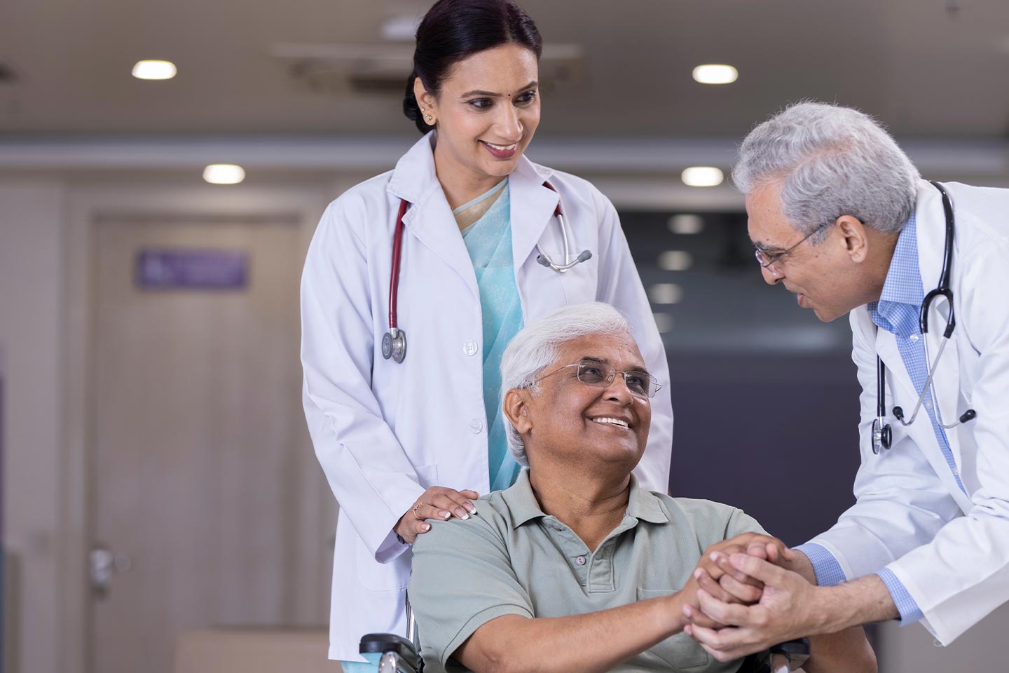 Photo of two doctors greeting a man in a wheelchair