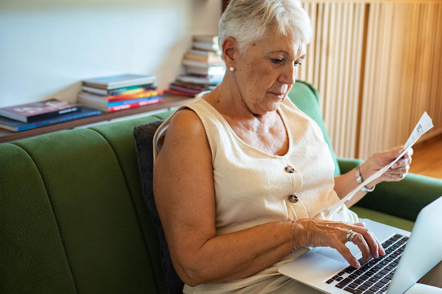 Image of a woman sitting on a sofa with a laptop reviewing a financial document