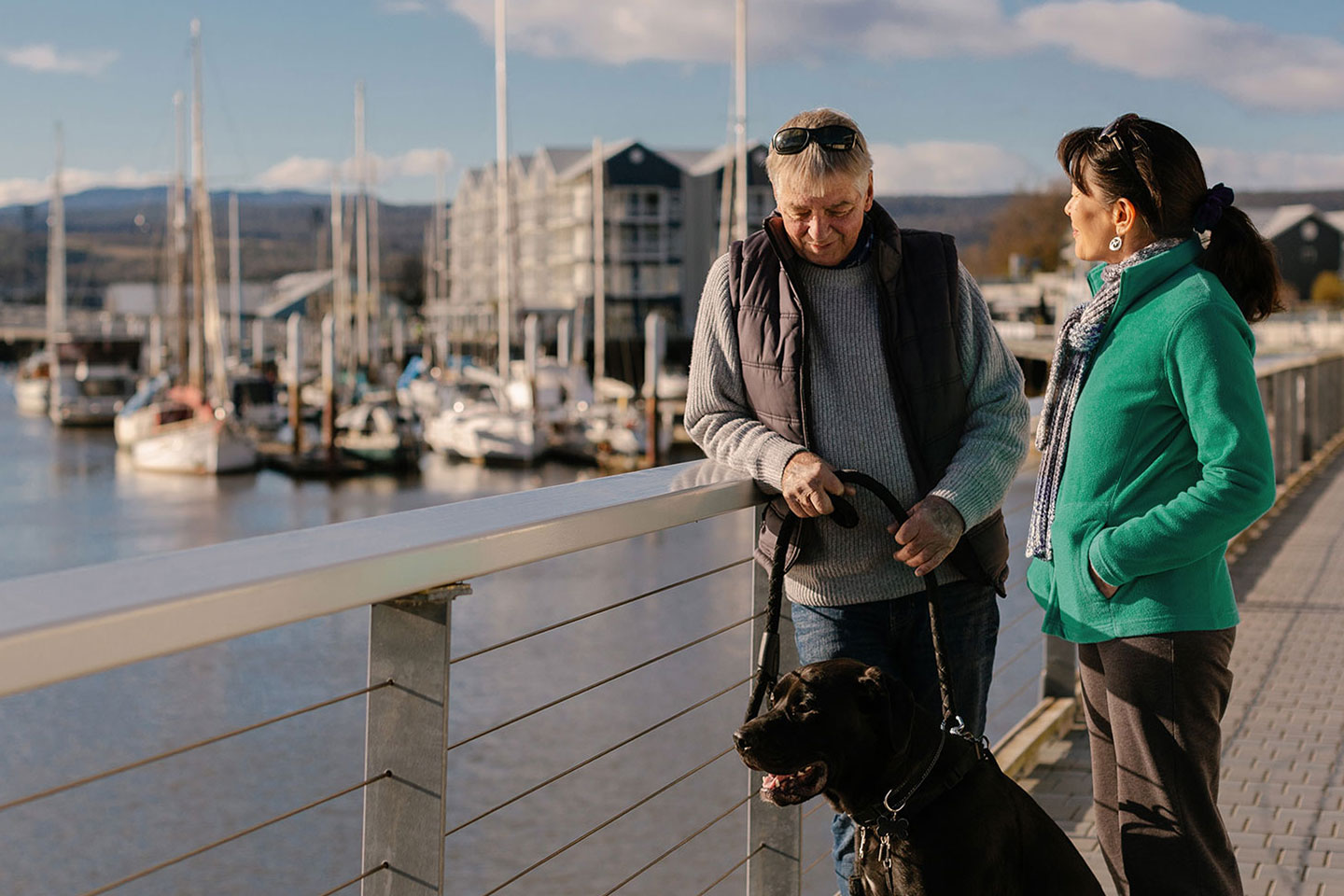 Photo of mature couple dogwalking on a dock